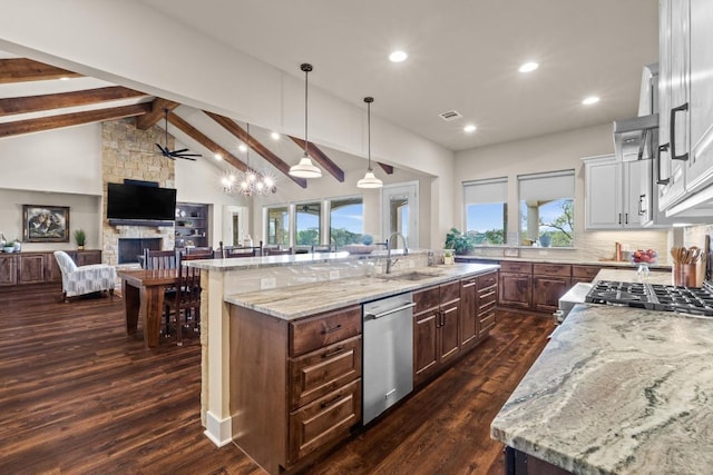 kitchen featuring a sink, open floor plan, dishwasher, a fireplace, and dark wood-type flooring
