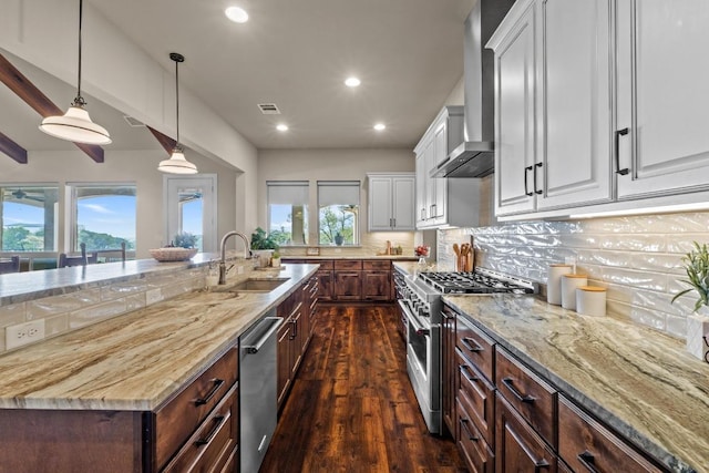 kitchen with white cabinets, dark wood finished floors, stainless steel appliances, a sink, and wall chimney exhaust hood