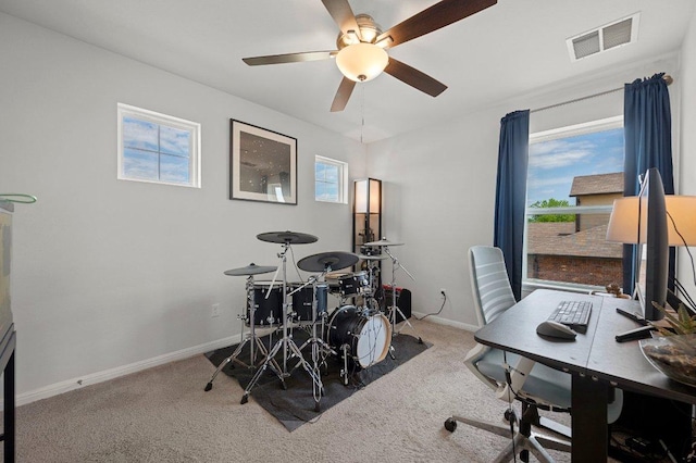 carpeted office with baseboards, visible vents, ceiling fan, and a healthy amount of sunlight