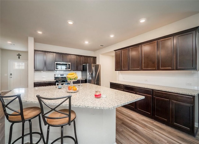 369 Empress Tree Dr, Leander, TX 78641 - kitchen with stainless steel appliances, dark brown cabinetry, light stone counters, and recessed lighting