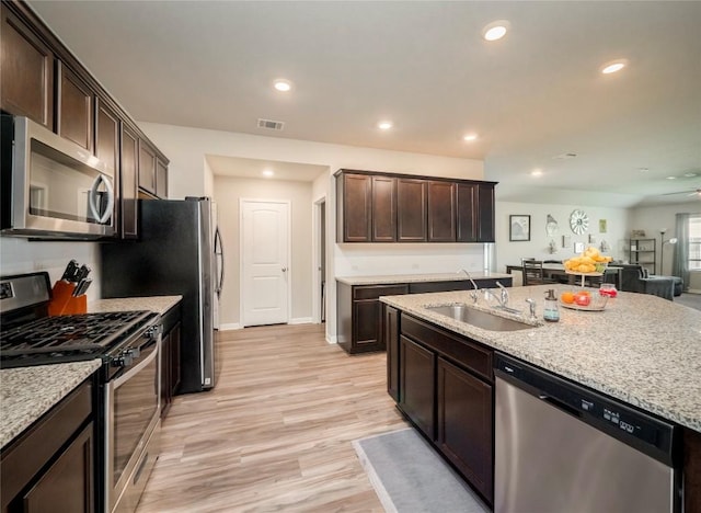 369 Empress Tree Dr, Leander, TX 78641 - kitchen featuring stainless steel appliances, a sink, dark brown cabinets, light stone countertops, and recessed lighting
