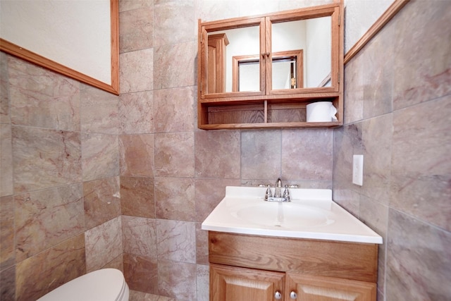 half bath with toilet, vanity, and tile walls
