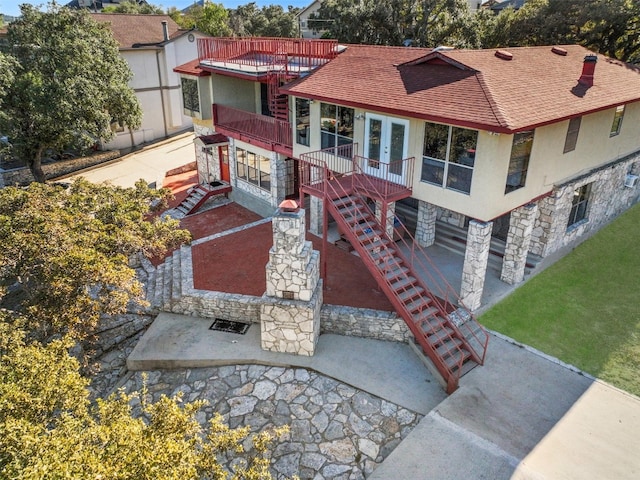 mediterranean / spanish house with french doors, stone siding, a shingled roof, stairway, and stucco siding