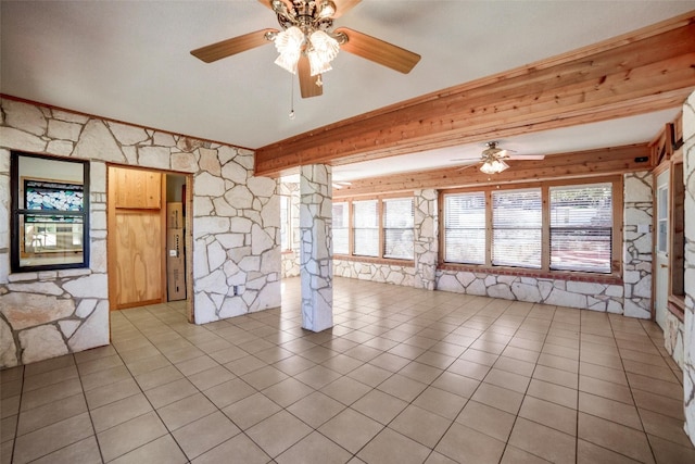spare room featuring decorative columns, wood walls, ceiling fan, and light tile patterned floors