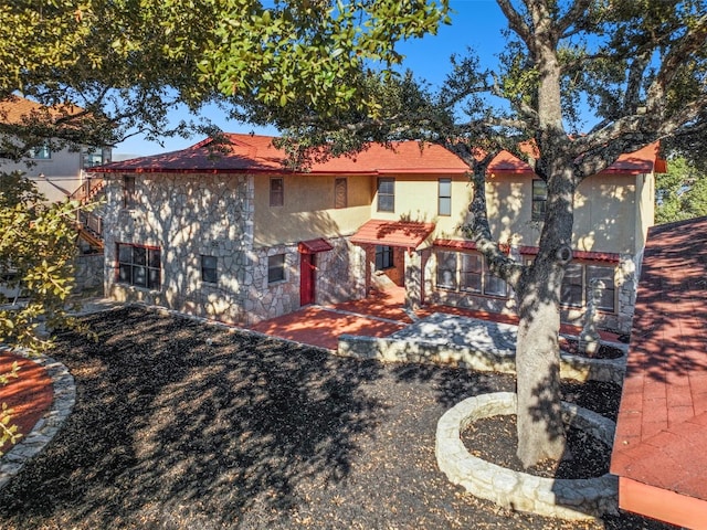 back of property with a patio area, stone siding, and stucco siding