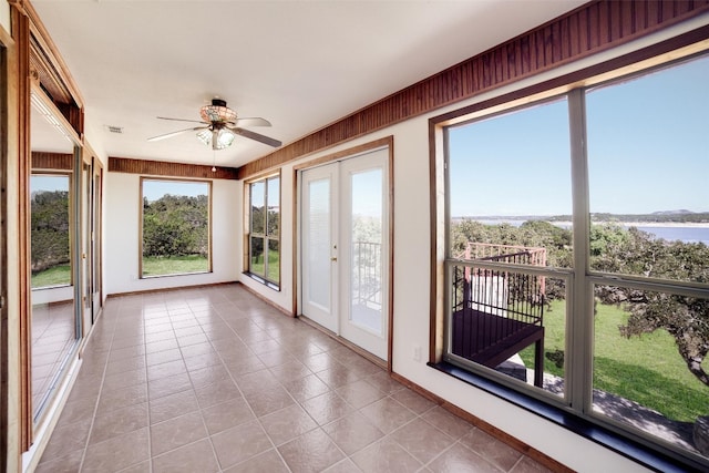 unfurnished sunroom with tile patterned floors, visible vents, a water view, french doors, and baseboards