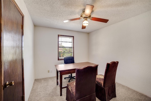 carpeted home office featuring a textured ceiling and ceiling fan