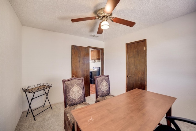 office area with a textured ceiling, visible vents, a ceiling fan, and light carpet
