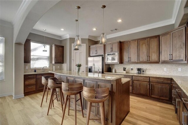 1621 Enfield Rd Unit B, Austin, TX 78703 - kitchen with stainless steel fridge with ice dispenser, light wood-type flooring, a kitchen island, a breakfast bar, and tasteful backsplash