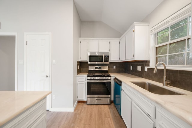 kitchen featuring tasteful backsplash, lofted ceiling, stainless steel appliances, and a sink