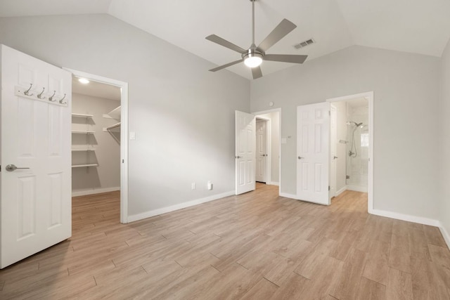 unfurnished bedroom featuring light wood finished floors, vaulted ceiling, visible vents, and a spacious closet