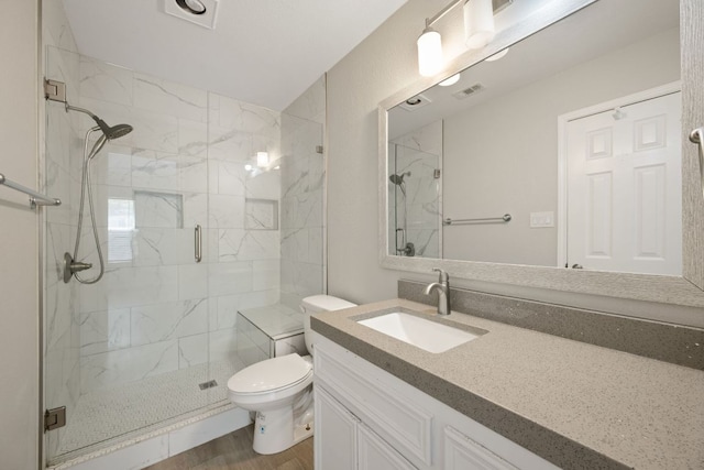 bathroom with wood finished floors, visible vents, toilet, vanity, and a marble finish shower