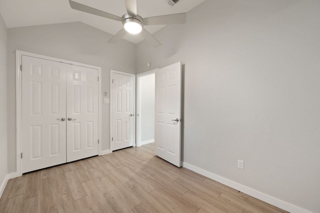 unfurnished bedroom featuring lofted ceiling, a closet, light wood finished floors, and baseboards