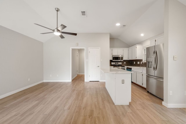 kitchen featuring vaulted ceiling, tasteful backsplash, light countertops, white cabinets, and appliances with stainless steel finishes