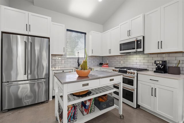kitchen featuring a sink, white microwave, backsplash, range with two ovens, and freestanding refrigerator