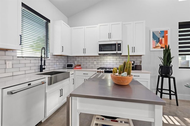 kitchen with a sink, tasteful backsplash, white cabinetry, lofted ceiling, and dishwasher