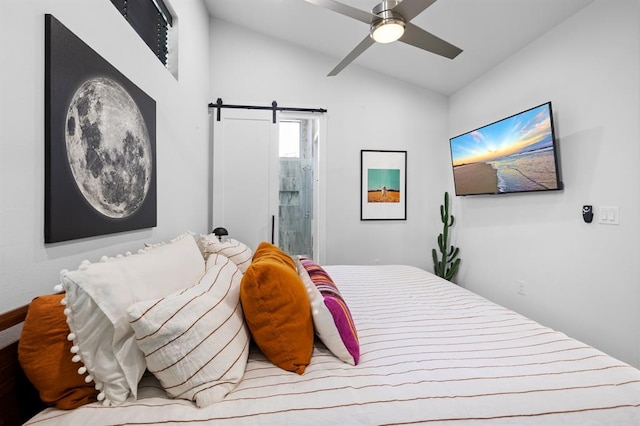bedroom with connected bathroom, a barn door, vaulted ceiling, and a ceiling fan