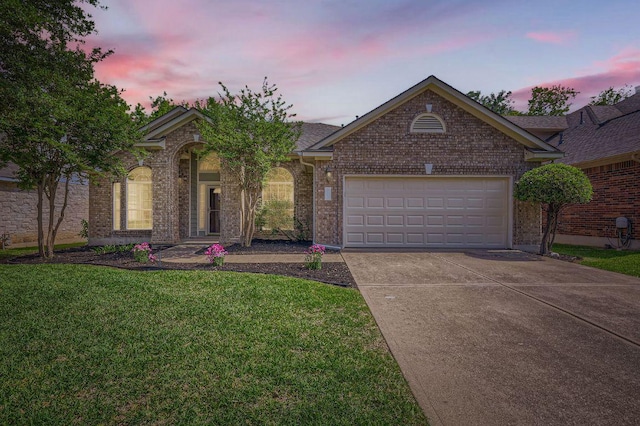 view of front facade featuring driveway, brick siding, an attached garage, and a lawn