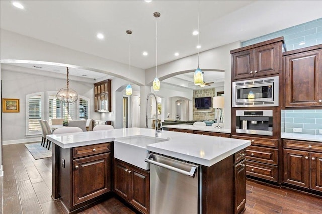 205 Bisset Ct, Austin, TX 78738 - kitchen with appliances with stainless steel finishes, arched walkways, light countertops, open floor plan, and dark wood finished floors