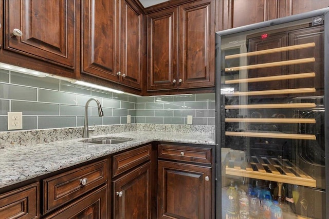 205 Bisset Ct, Austin, TX 78738 - kitchen with wine cooler, light stone countertops, decorative backsplash, and dark brown cabinetry