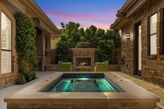 205 Bisset Ct, Austin, TX 78738 - pool at dusk featuring an outdoor stone fireplace, a swimming pool, and a patio
