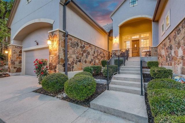 29047 Hobblebush, San Antonio, TX 78260 - exterior entry at dusk with stone siding, stucco siding, a garage, and concrete driveway