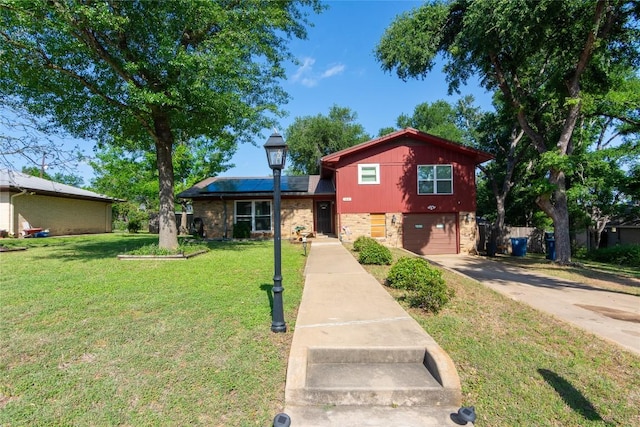 1212 Lake Terrace Dr, Elgin, TX 78621 - tri-level home featuring concrete driveway, stone siding, an attached garage, a front yard, and solar panels