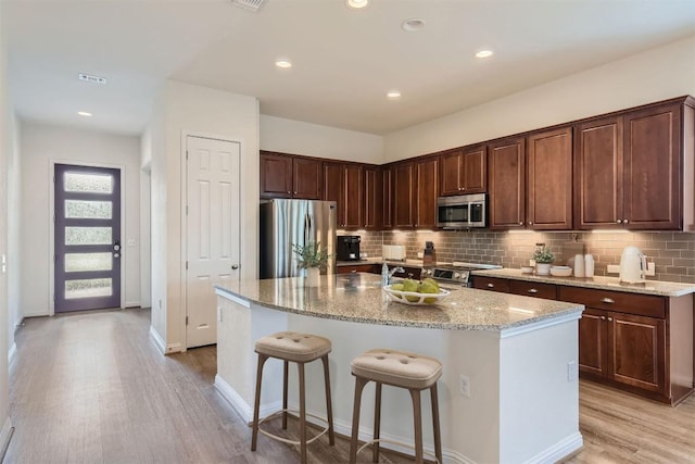 9945 Comely Bnd, Manor, TX 78653 - kitchen with stainless steel appliances, light wood finished floors, decorative backsplash, light stone countertops, and recessed lighting