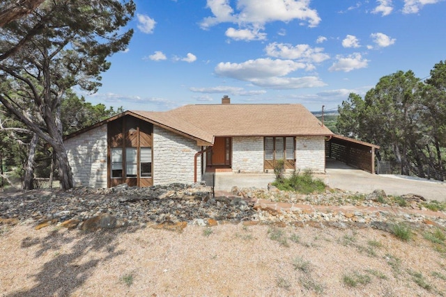 21009 Fawn Ridge Dr, Lago Vista, TX 78645 - view of front of house featuring roof with shingles, a carport, driveway, stone siding, and a chimney