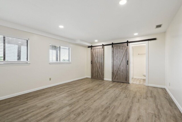 21009 Fawn Ridge Dr, Lago Vista, TX 78645 - interior space featuring a barn door, recessed lighting, visible vents, light wood-type flooring, and baseboards