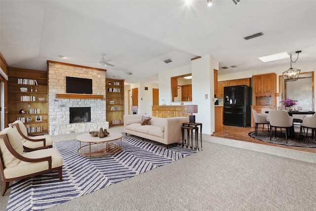 21009 Fawn Ridge Dr, Lago Vista, TX 78645 - living room with ceiling fan with notable chandelier, built in features, a fireplace, light colored carpet, and visible vents