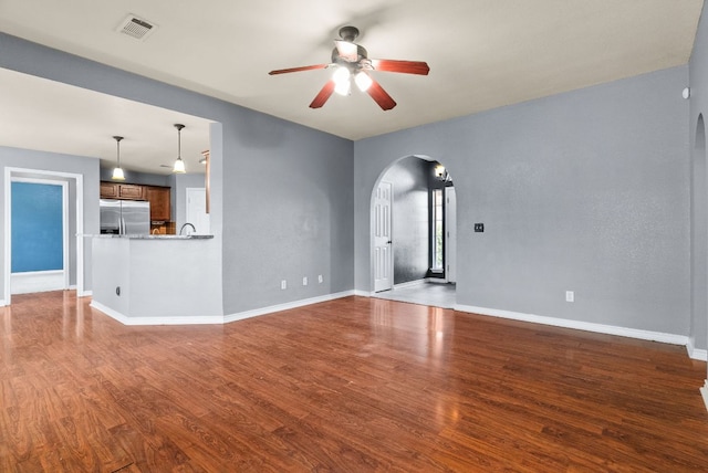 6060 County Road 3300, Kempner, TX 76539 - unfurnished living room with wood finished floors, visible vents, arched walkways, baseboards, and ceiling fan