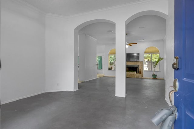 unfurnished living room with a fireplace, a ceiling fan, finished concrete flooring, ornamental molding, and baseboards