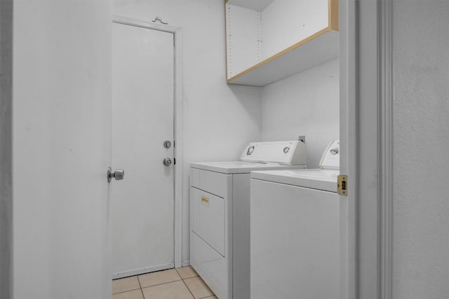 laundry area featuring washing machine and clothes dryer and light tile patterned flooring