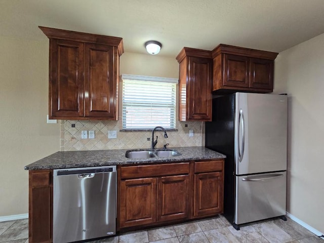 kitchen featuring appliances with stainless steel finishes, baseboards, decorative backsplash, and a sink