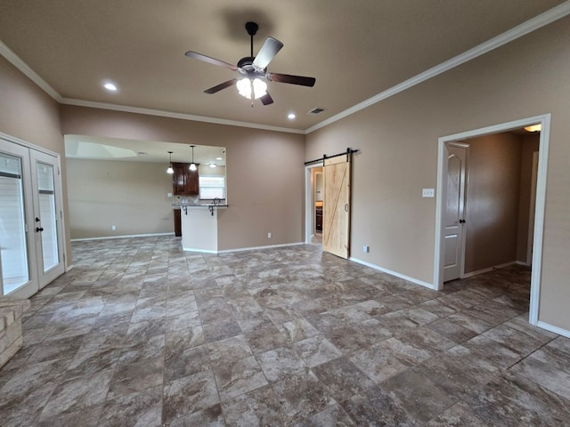 unfurnished living room with a barn door, ceiling fan, baseboards, and ornamental molding