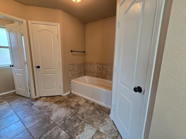 full bathroom with a bath and baseboards