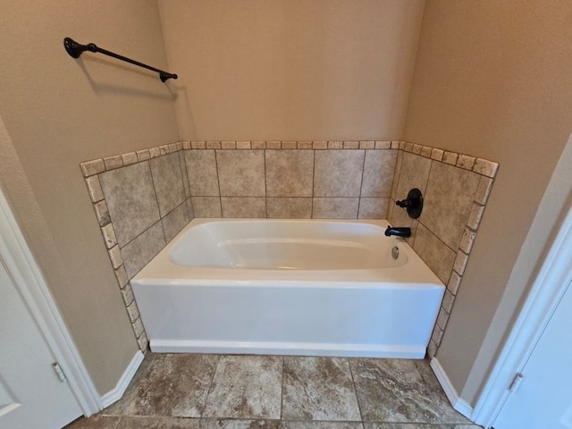 full bathroom with a bath and baseboards