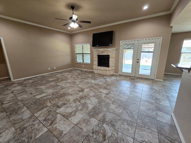 unfurnished living room featuring a ceiling fan, baseboards, a stone fireplace, and crown molding