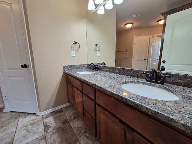 bathroom featuring double vanity, visible vents, baseboards, and a sink