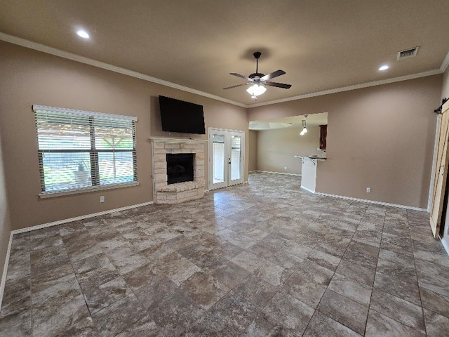 unfurnished living room featuring visible vents, a ceiling fan, crown molding, baseboards, and a fireplace