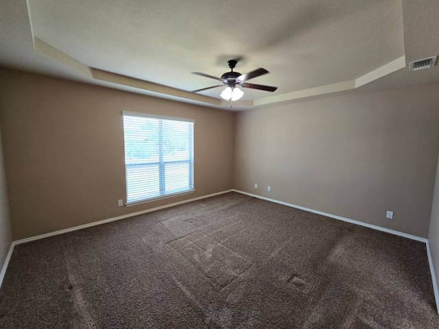 carpeted spare room featuring ceiling fan, baseboards, visible vents, and a raised ceiling