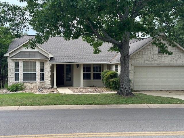 125 Whispering Wind Dr, Georgetown, TX 78633 - single story home with stone siding, a garage, driveway, and roof with shingles