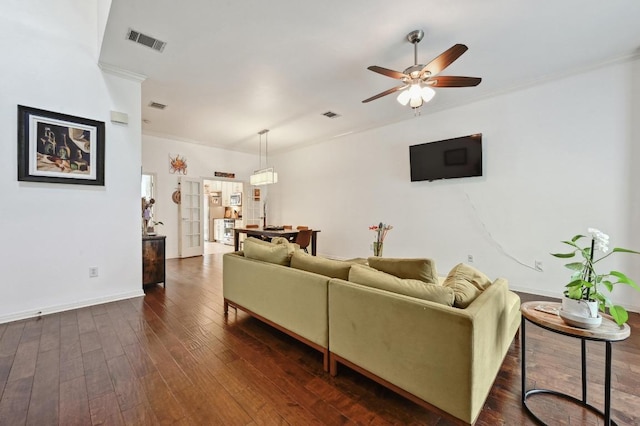 living room featuring dark wood-type flooring, visible vents, crown molding, and a ceiling fan