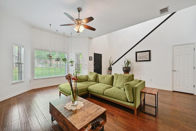 living area with visible vents, a ceiling fan, dark wood-type flooring, crown molding, and baseboards