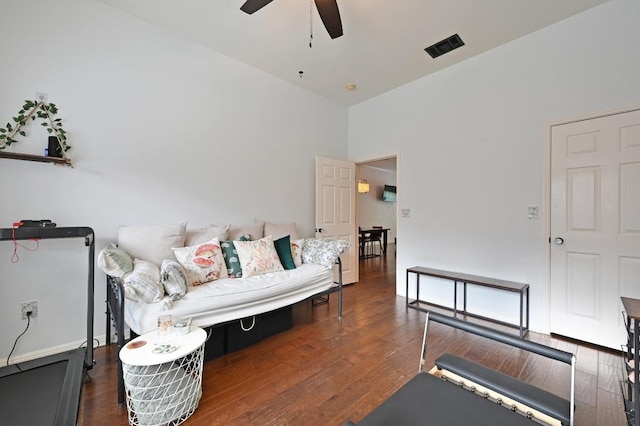 living room featuring wood finished floors, a ceiling fan, visible vents, and a high ceiling