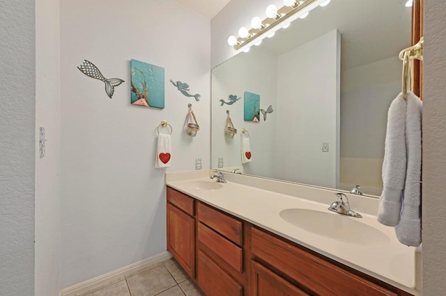 bathroom with tile patterned flooring, baseboards, a sink, and double vanity