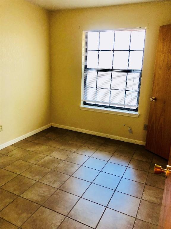 spare room featuring tile patterned floors and baseboards