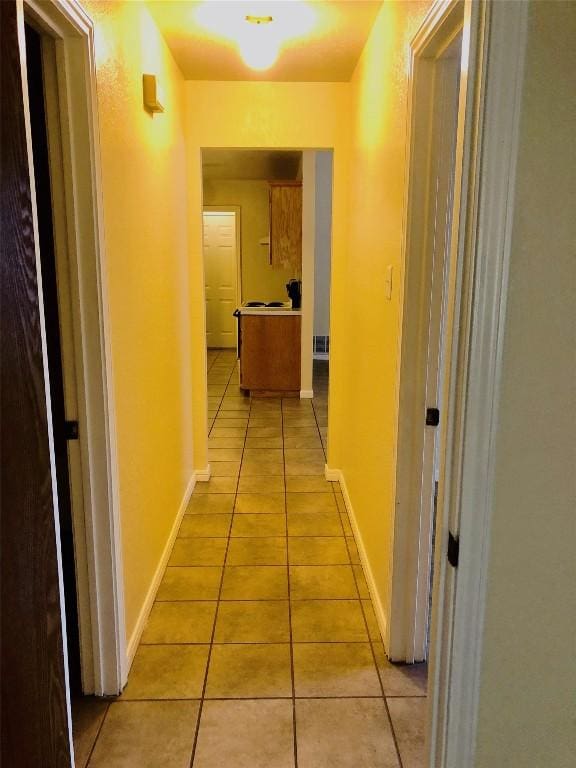 corridor with baseboards and light tile patterned floors