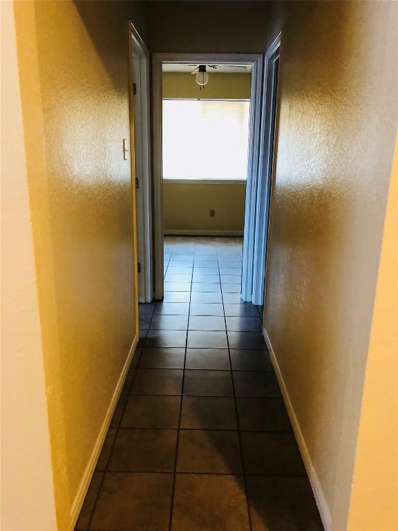 hall with dark tile patterned floors and baseboards